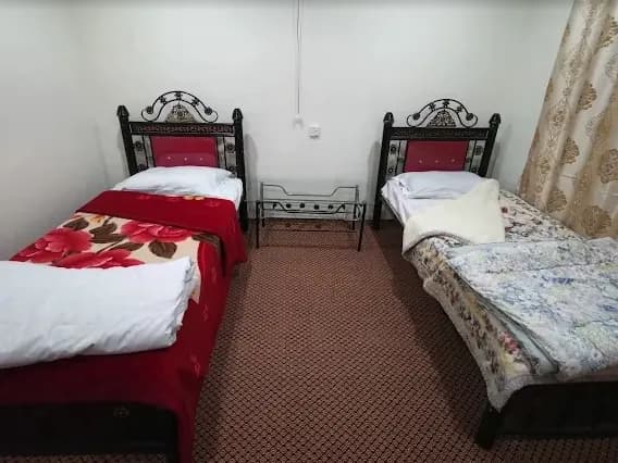 Two single beds made up in a plain room, with a small side table between them