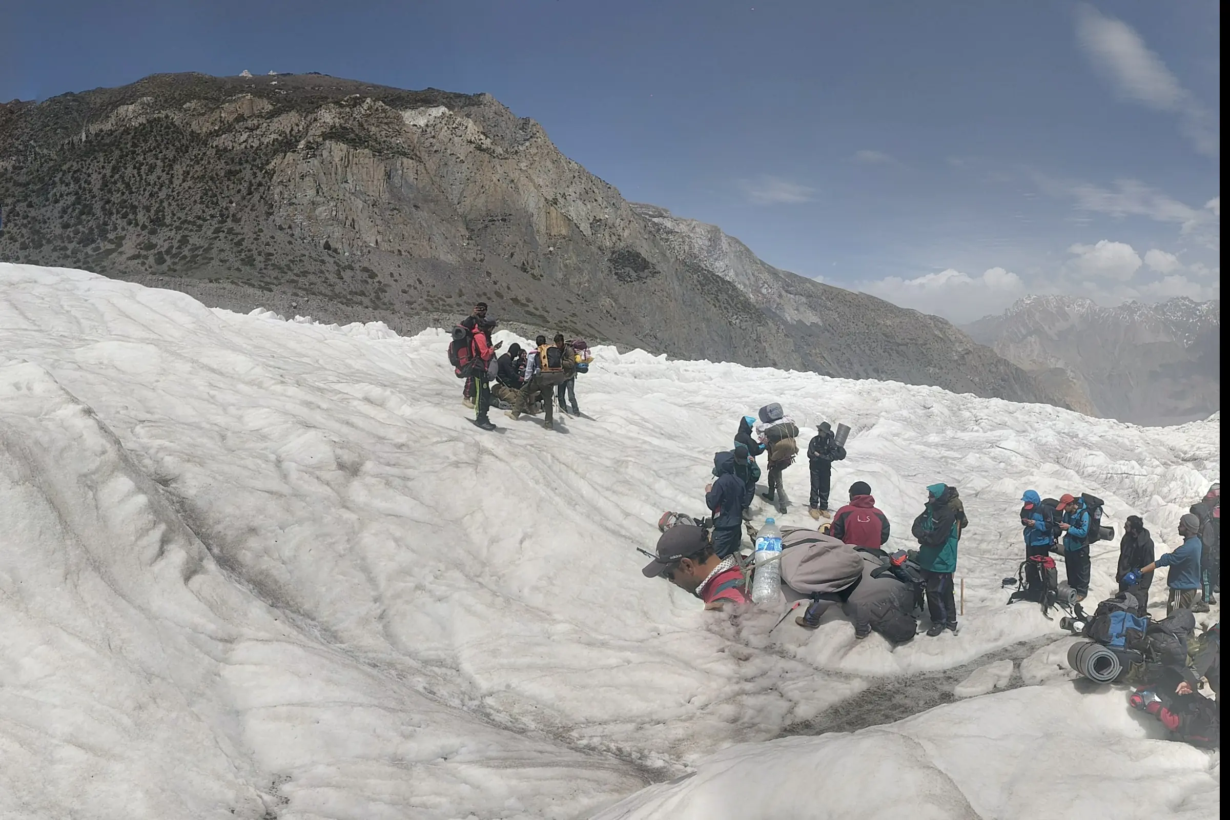 Trekkers and porters resting with their packs and loads on a glacier in the Karakoram